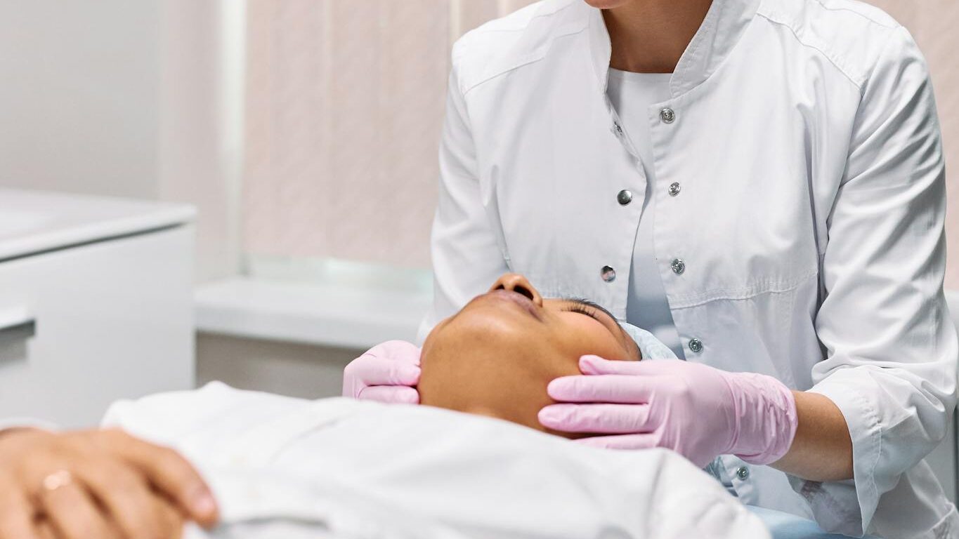 Beautician performing facial treatment in a spa setting, promoting relaxation and care.